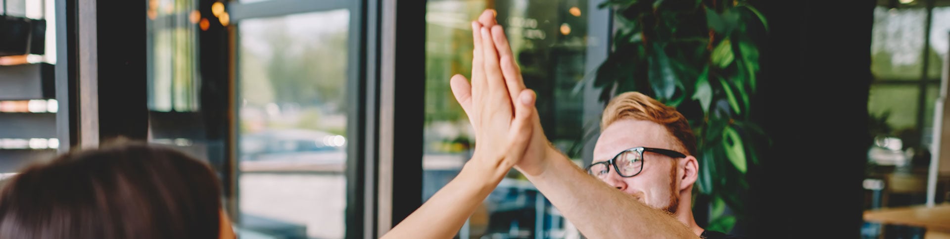 Zwei Menschen geben sich in einem offenen udn freundlichen Bürogebäude einen Handschlag